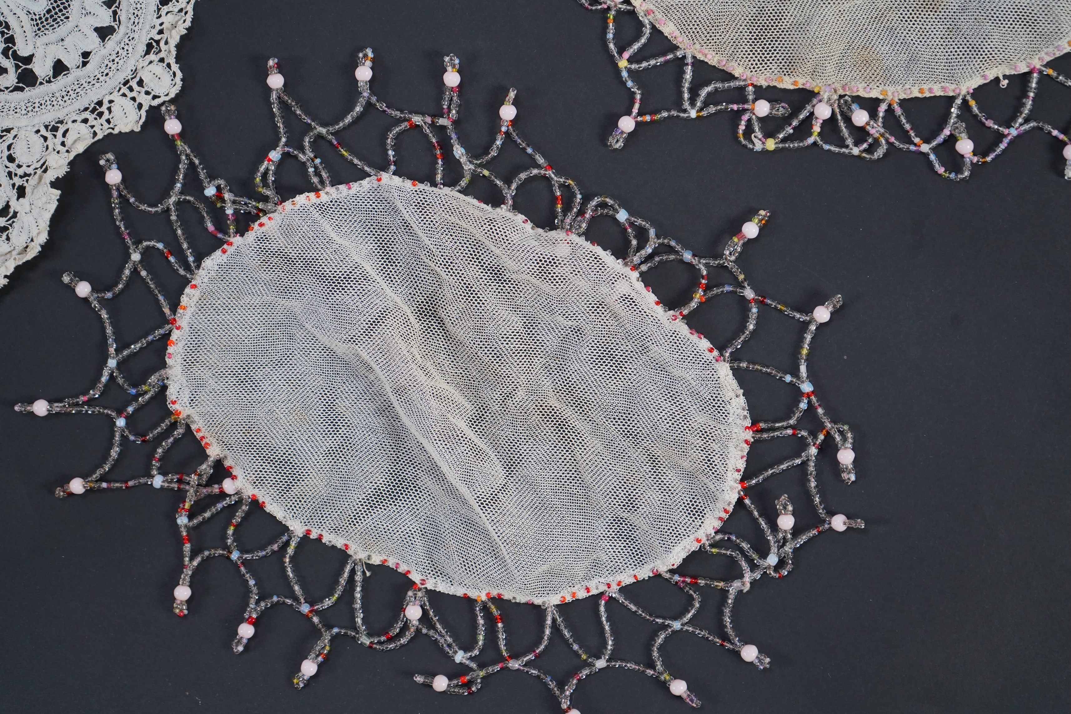 A white tape lace on net bed cover, a cream lace needle run panel, three Brussels bobbin lace collars, a lappet and two beaded tea pot covers, bed cover 200cm x 250cm. Condition - the bedcover has damage to the netting,